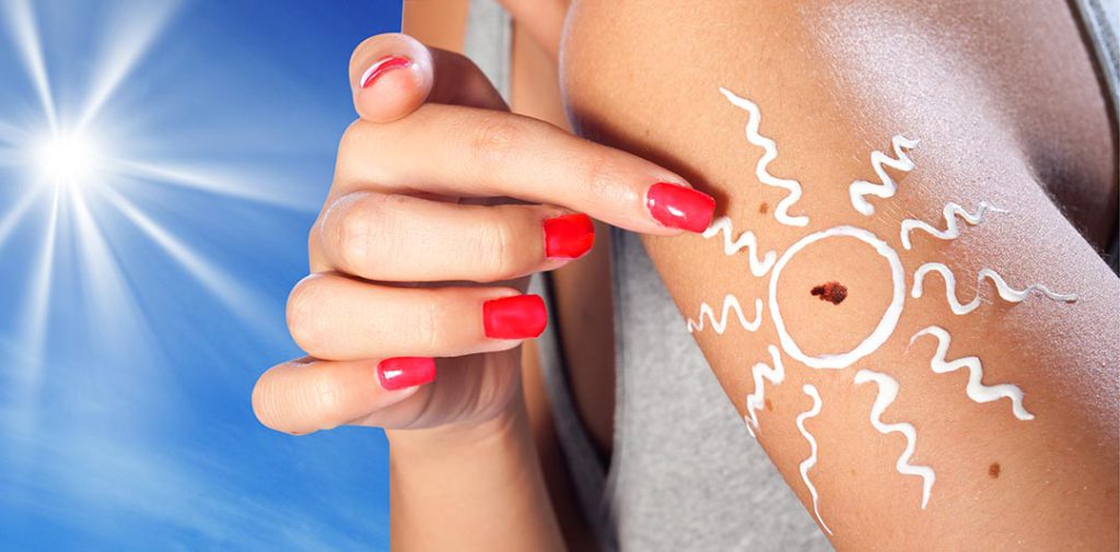 melanoma skin cancer on woman arm with sun in the background